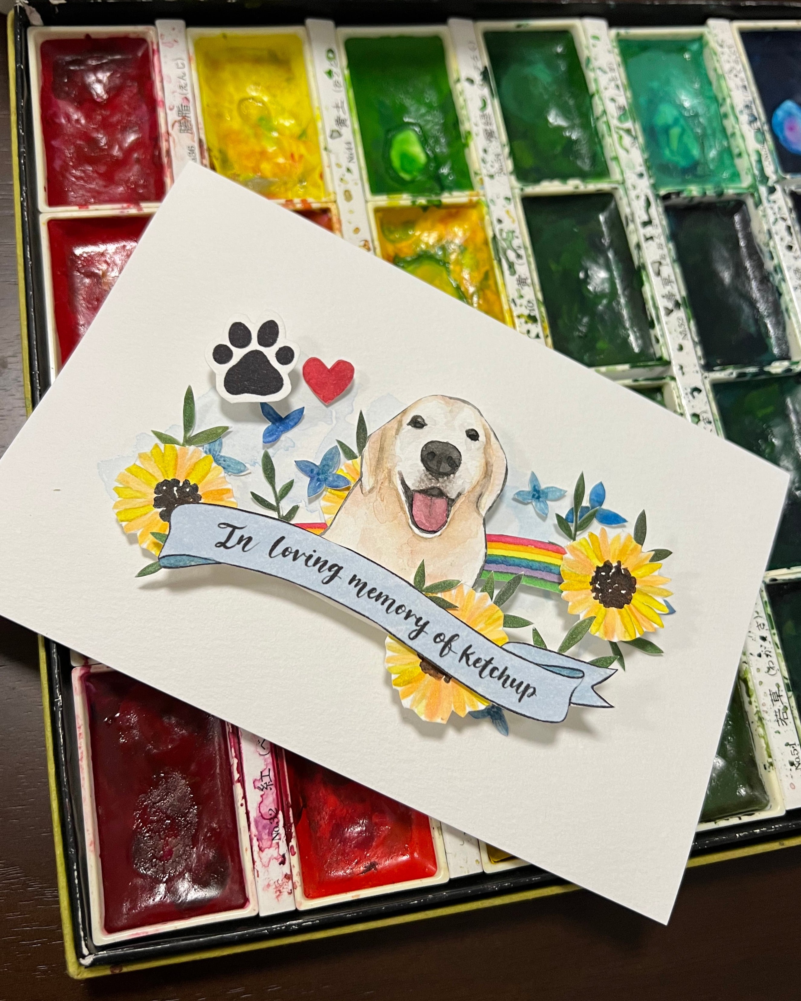 Memorial card with a dog illustration and rainbow banner on a watercolor set.