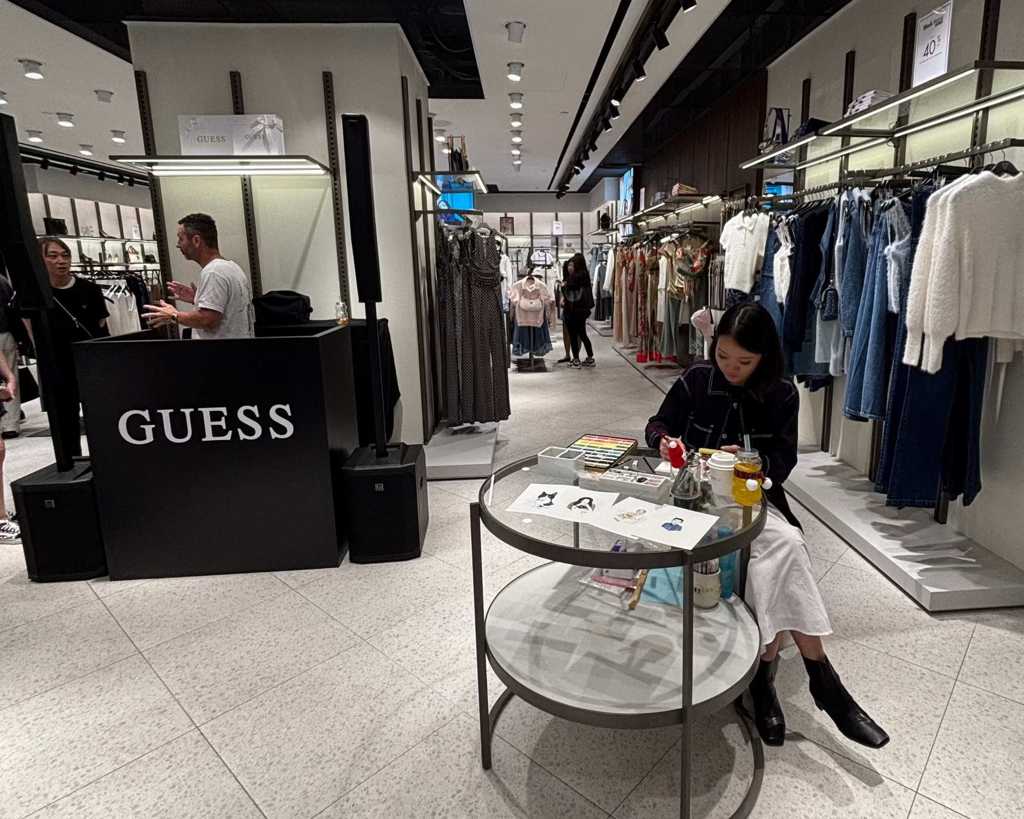 Artist sitting at a round table in a Guess store painting.