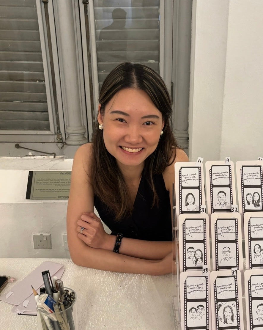 Woman sitting at a table with a display of small cards, smiling.