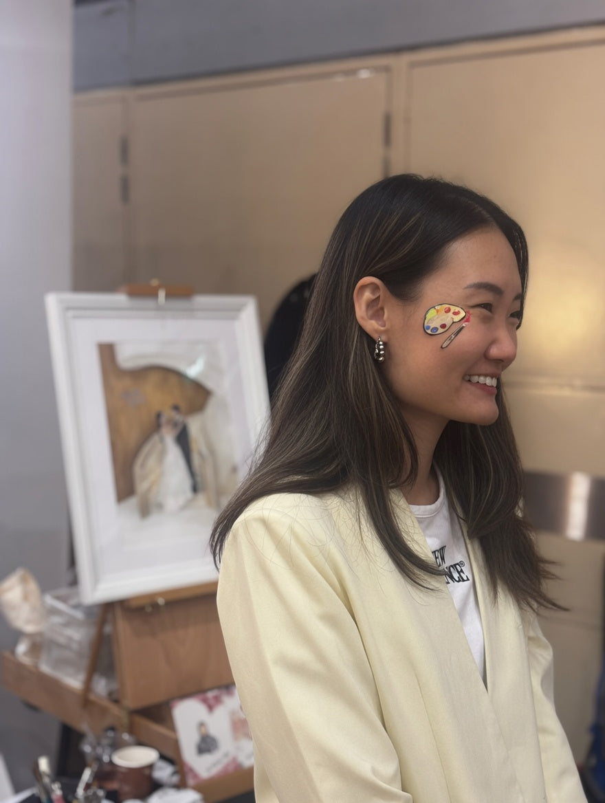 Woman with art-themed makeup smiling in a casual indoor setting