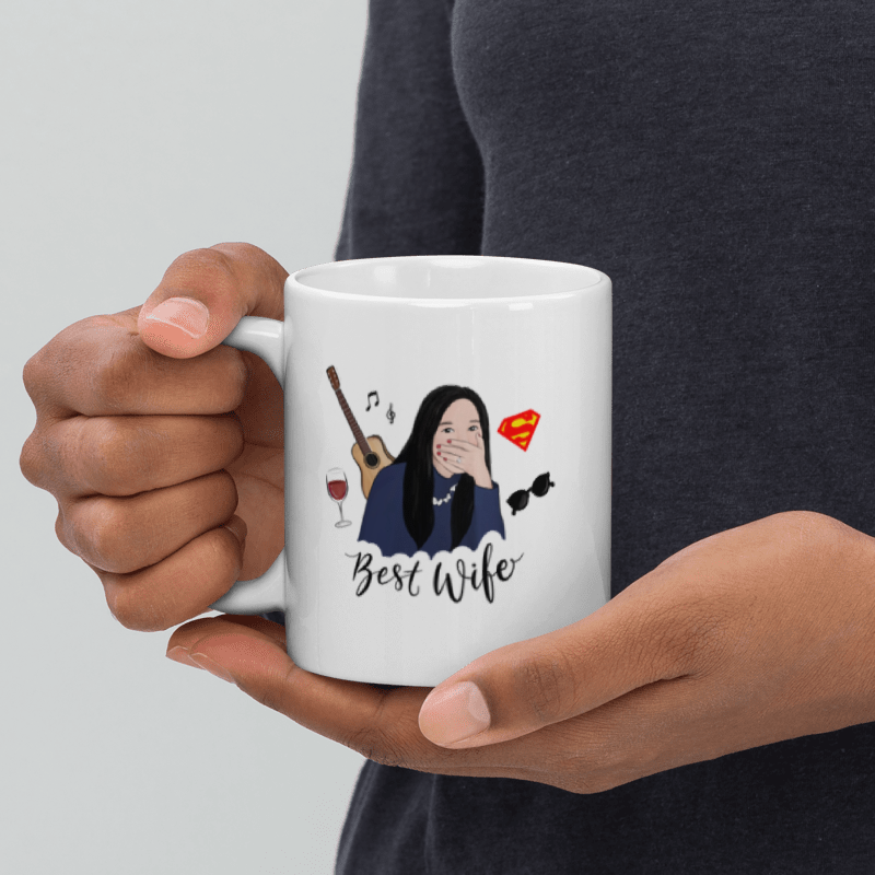 Person holding a white mug with illustrations and text, against a plain background