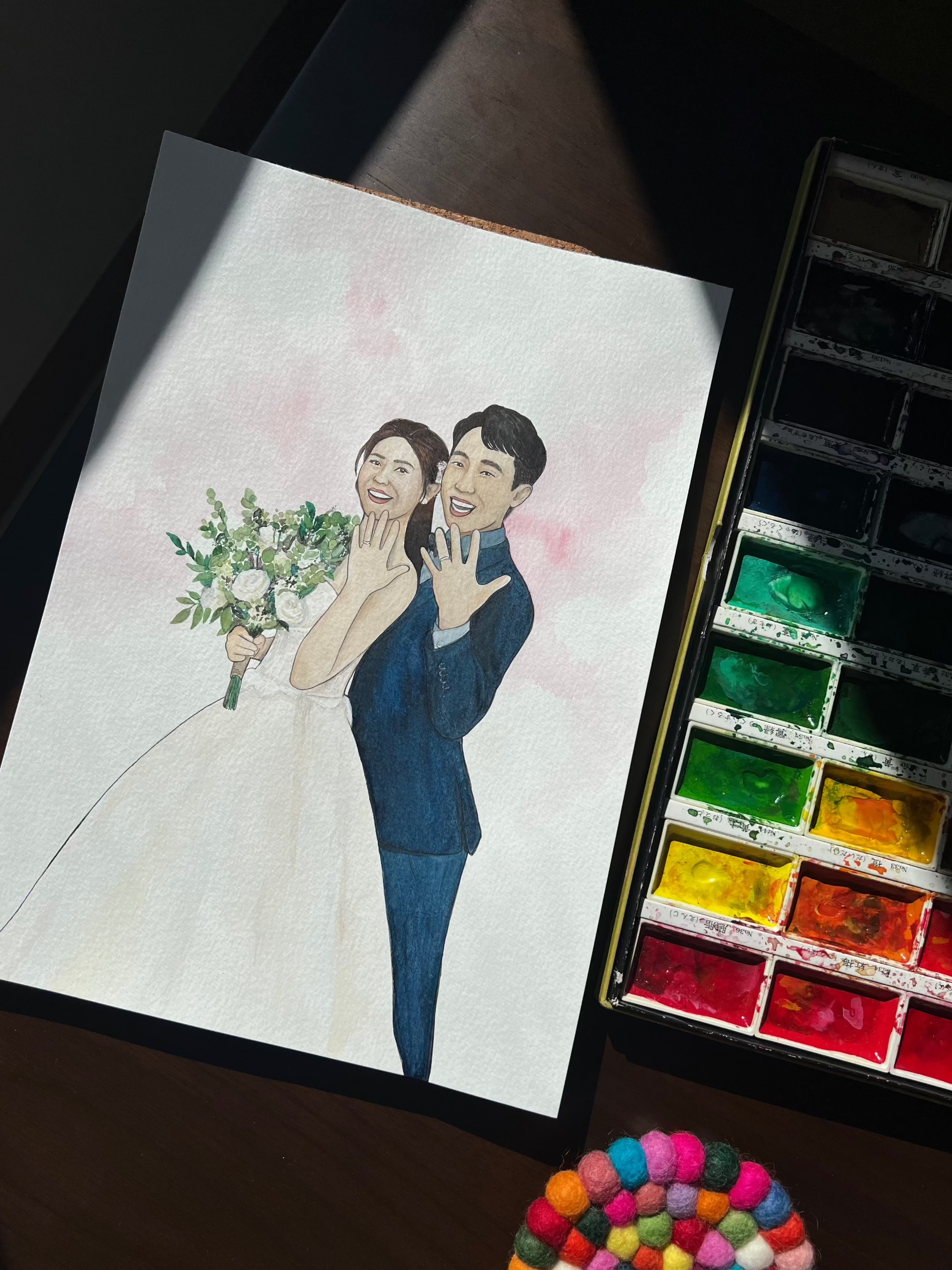 Hand-drawn illustration of a couple on paper with watercolor paints and pom-poms.