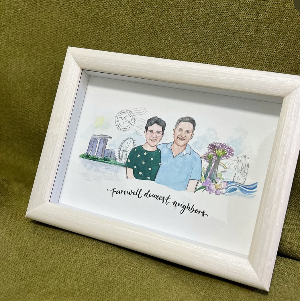 White framed drawing of a couple with singapore skyline  on a green surface