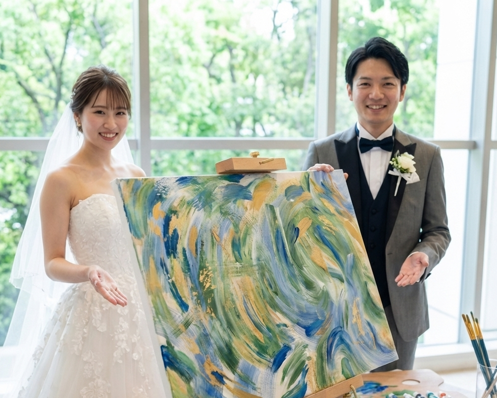 Man and woman holding a painting in a room with large windows