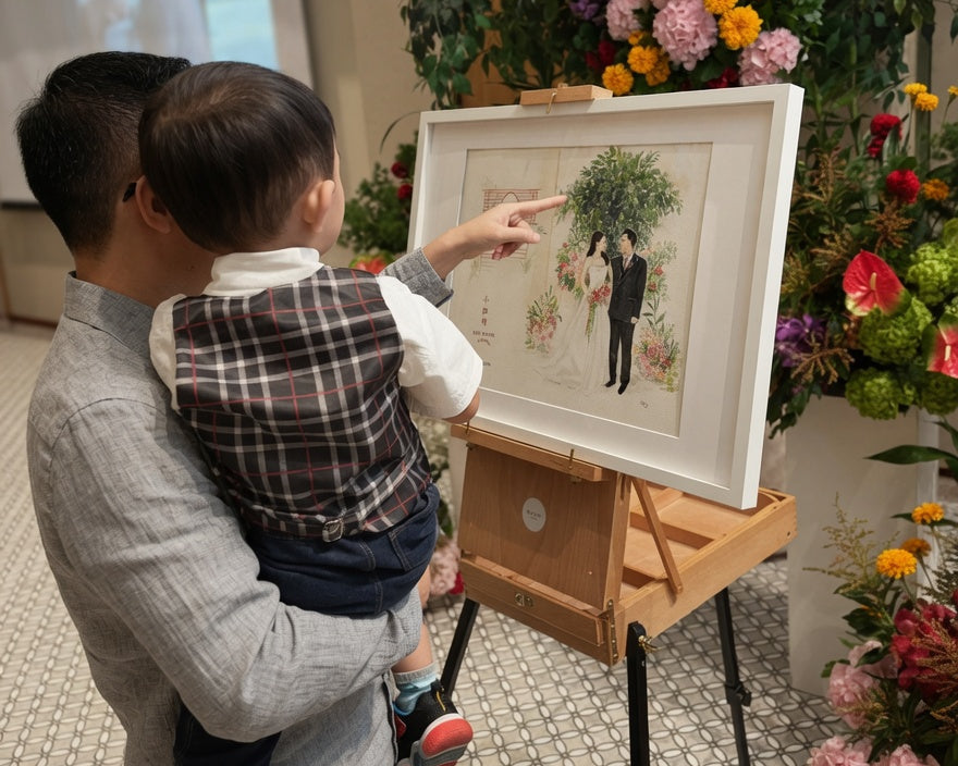 Man holding a child as they point at a framed picture of a couple among flowers.