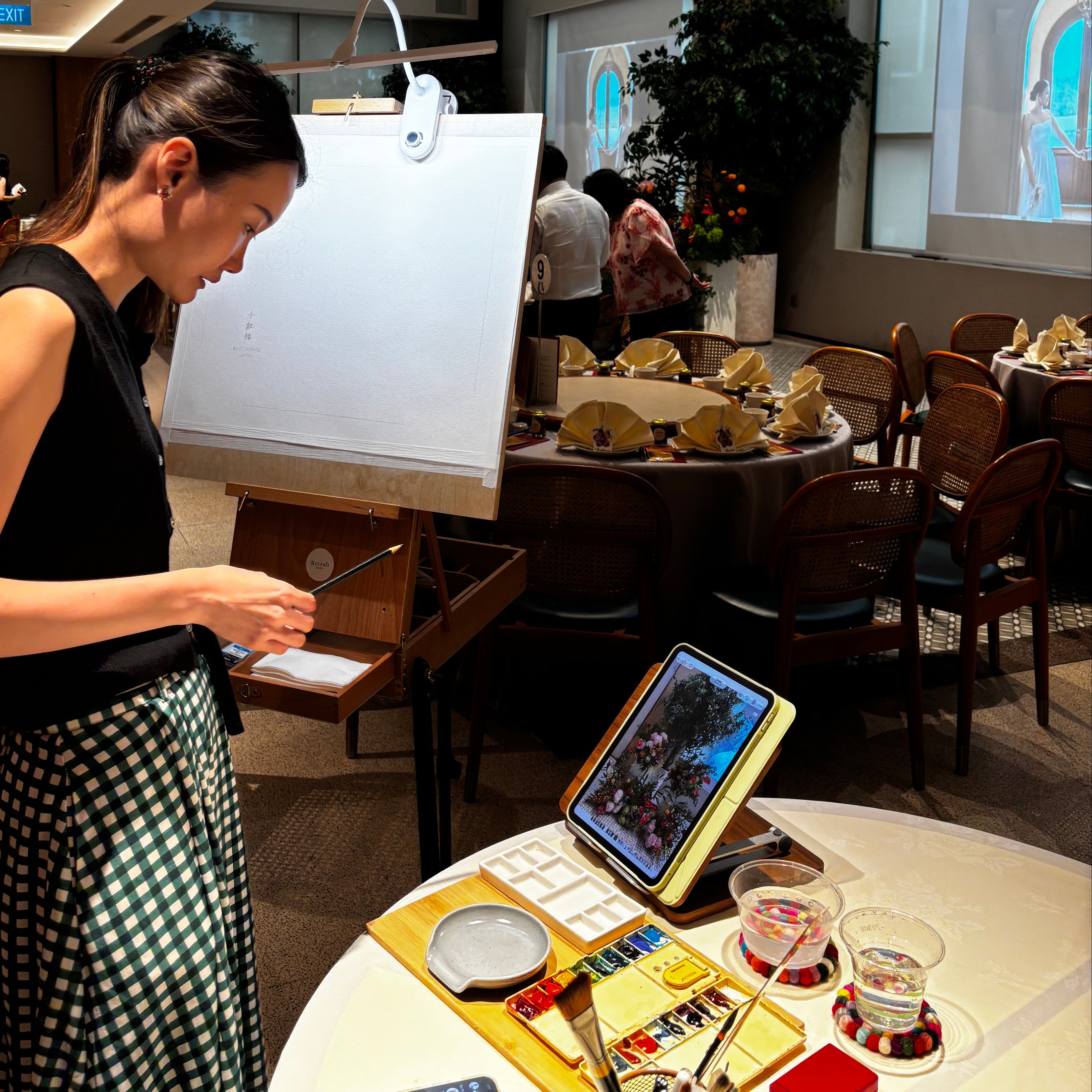 Woman sitting at a table in a restaurant with a smartphone, looking up.