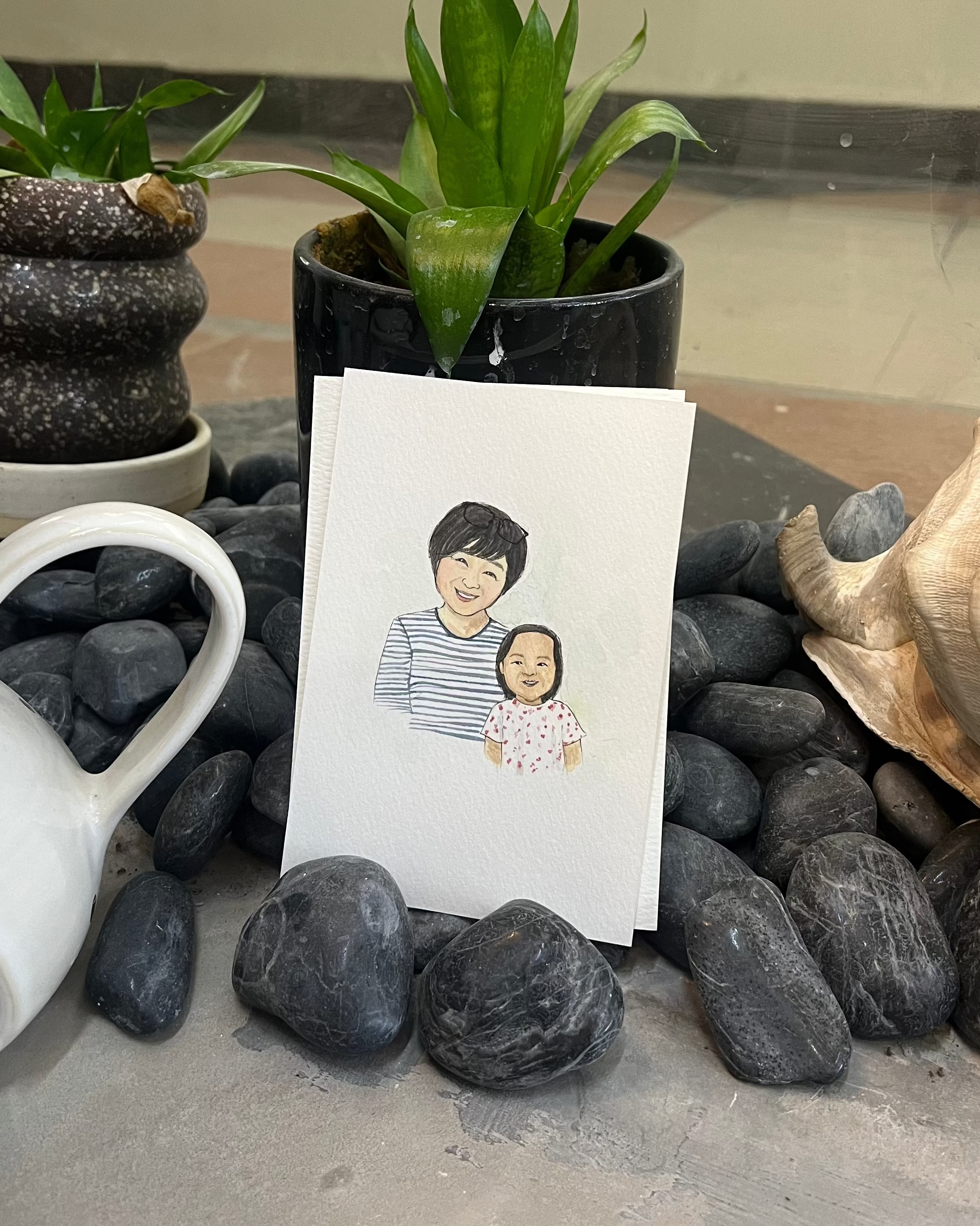 Card with a portrait of a man and a child on a stone surface with plants and a teapot.