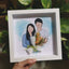 Couple portrait drawing holding a mini dried flower bouquet in a white frame for gifting.