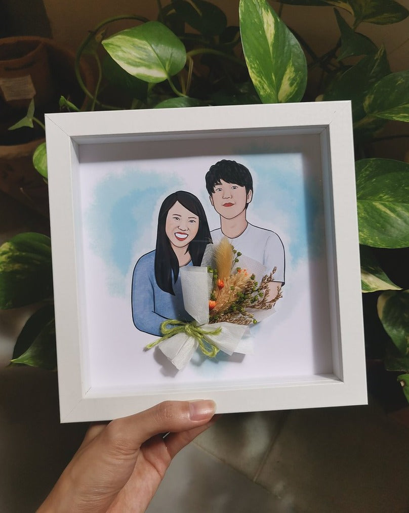 Couple portrait drawing holding a mini dried flower bouquet in a white frame for gifting.