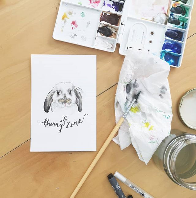 Painting a rabbit pet watercolor portrait illustration with paintbrush and palette.