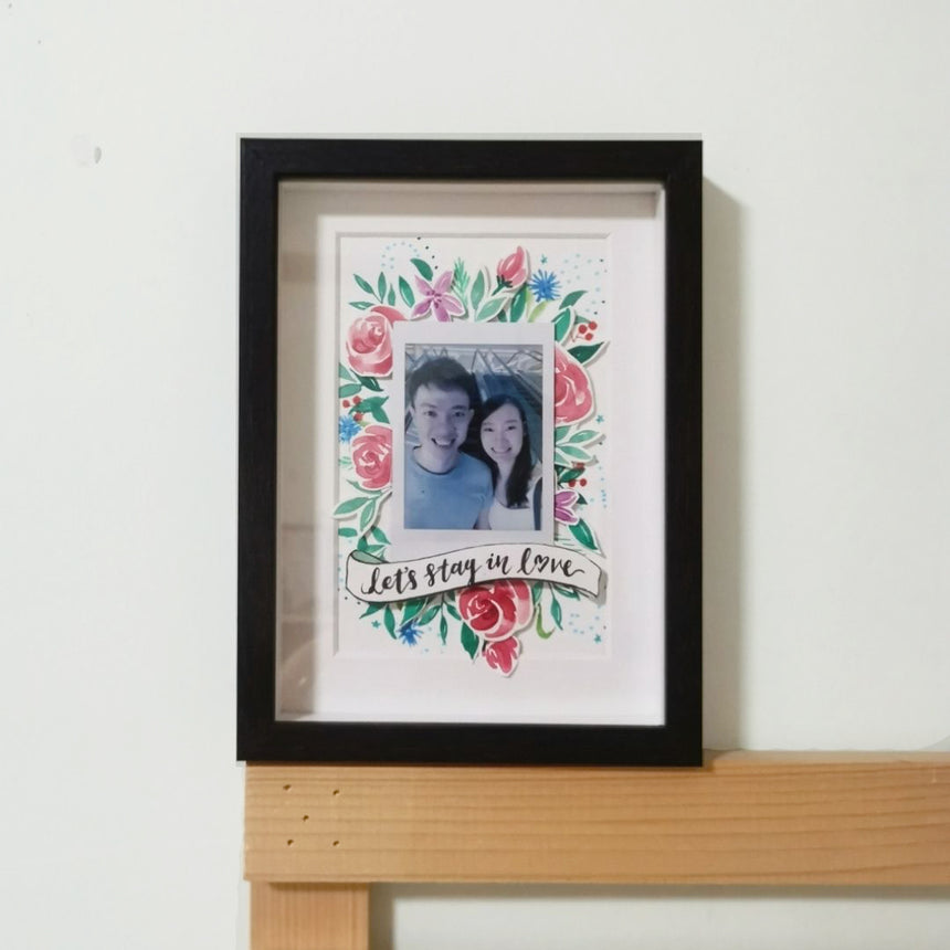 Watercolor rose floral papercut design with a couple photo in a black frame.