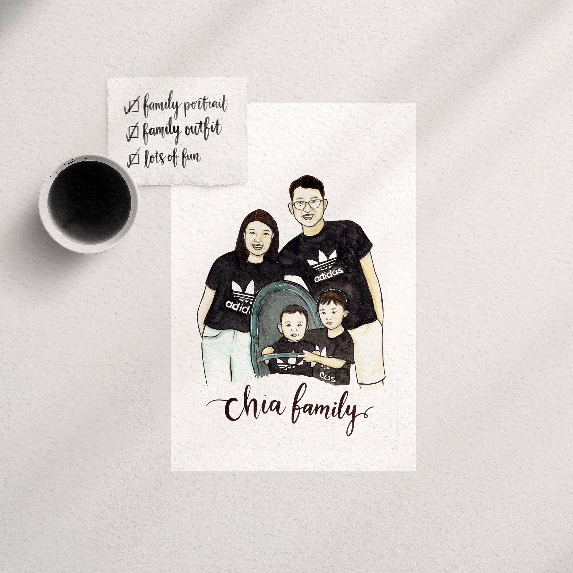 A custom family watercolor portrait illustration placed on a table next to a cup of coffee, with the image depicting two adults and two children wearing black tops and white bottoms, with the text 'Chia family' at the bottom.