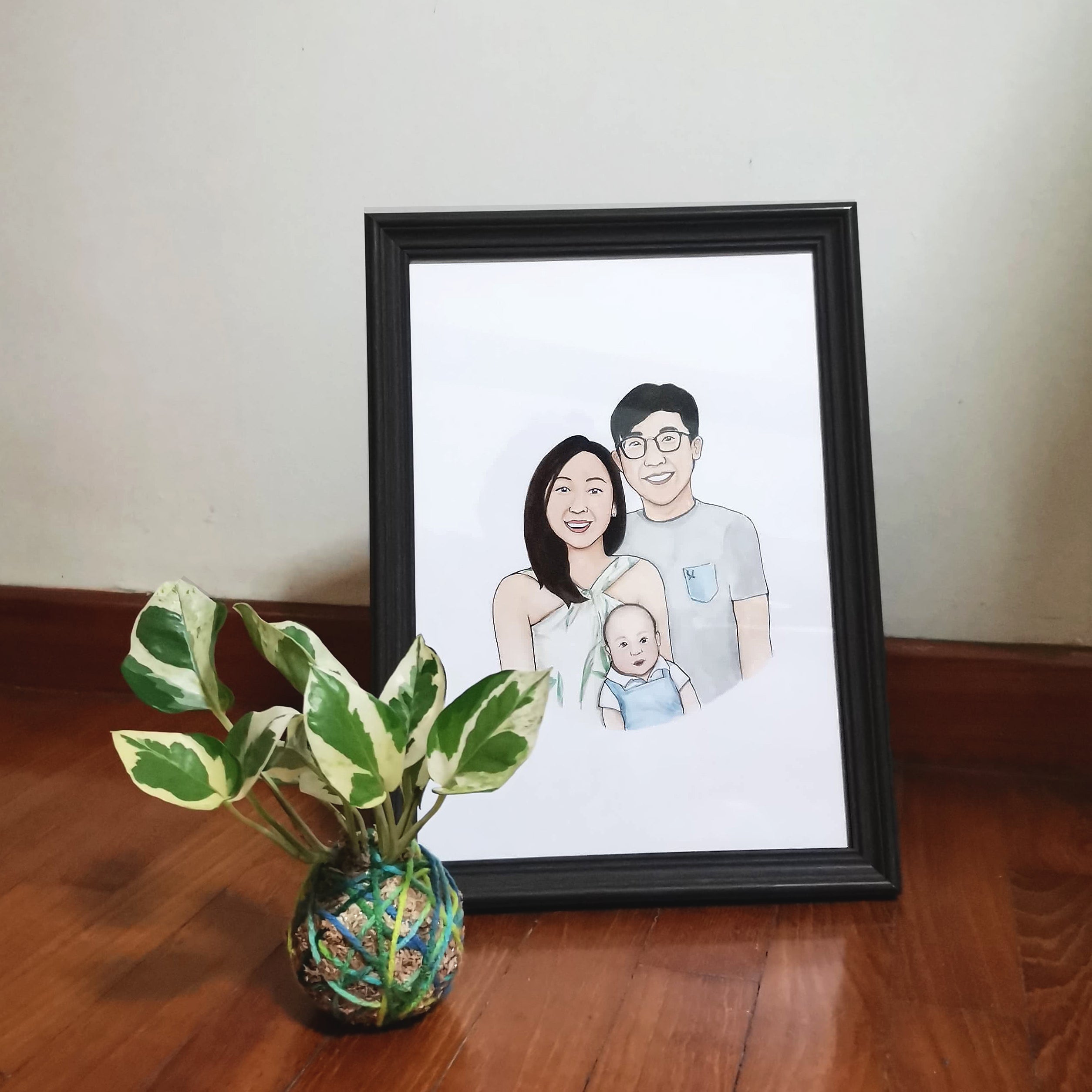 A family of three watercolor portrait in a black frame.